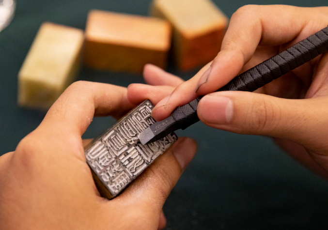 2023年10月18日，華東師范大學(xué)書(shū)法篆刻專業(yè)的學(xué)生在現(xiàn)場(chǎng)篆刻。當(dāng) 天，華東師范大學(xué)“大夏百詠”篆刻創(chuàng)作啟動(dòng)暨韓天衡獎(jiǎng)學(xué)金頒發(fā)儀式舉行。 “大夏百詠”篆刻創(chuàng)作項(xiàng)目是2023—2024年華東師范大學(xué)校園文化重點(diǎn)項(xiàng) 目，旨在傳承文脈，彰顯底蘊(yùn)。